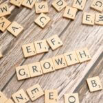 Wooden tiles spelling ETF growth on a wooden surface, symbolizing investment strategy.